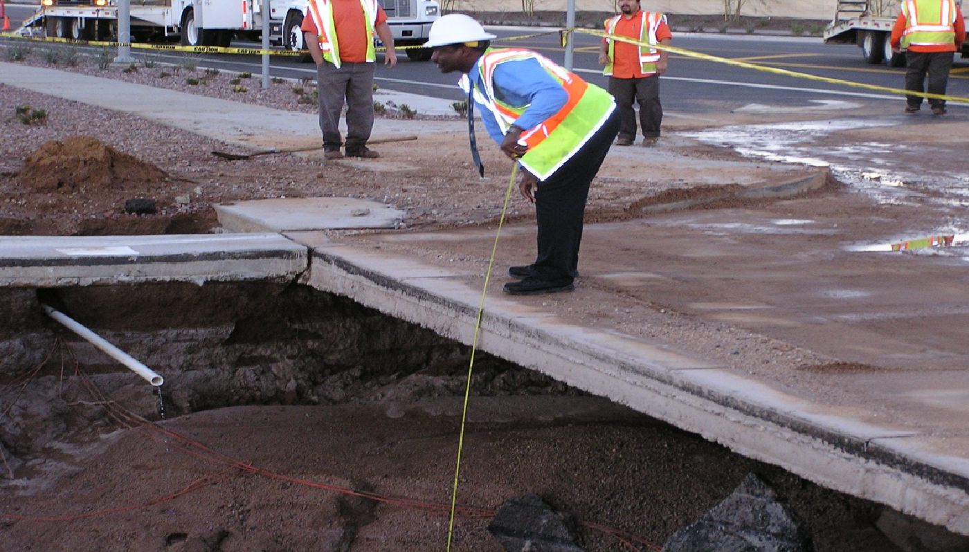 Morgan taking a measurement of the depth to a water main after a break